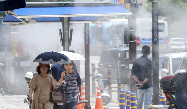 장맛비가 소강 상태를 보인 3일 오후 부산 동구에서 시민들이 쿨링포그 아래를 지나며 더위를 식히고 있다. 쿨링포그는 미세 물 분자가 더운 공기와 만나 기화할 수 있도록 물을 뿌려 온도를 3~5도 낮추는 시스템이다. 김종진 기자 kjj1761@