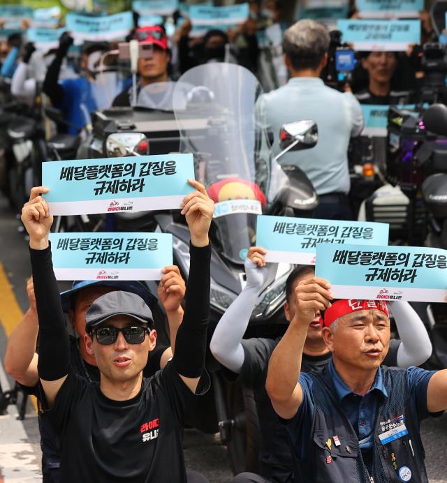 민주노총 공공운수노조 라이더유니온지부 조합원들이 지난 6월 21일 국회의사당 역 앞에서 '배달라이더 &times; 배달상점주 플랫폼 갑질 규탄대회'를 열고 구호를 외치며 피켓을 올리고 있다. 연합뉴스