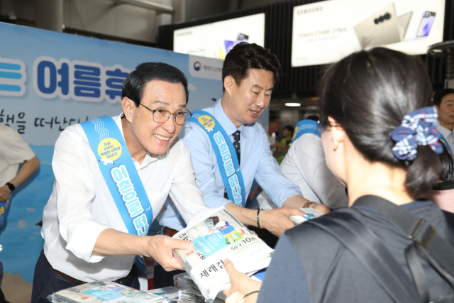 노동진 수협중앙회장(왼쪽)이 16일 SRT 수서역에서 열린 '여름휴가 어촌에서 보내기 캠페인'에서 방송인 남희석 씨와 함께 시민들에게 어촌 관광 안내 책자와 함께 수산물을 나눠주고 있다. 수협 제공