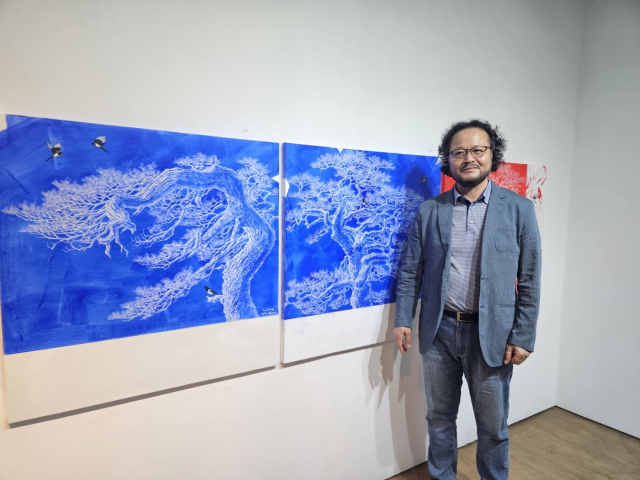 구명본 작가가 새로운 방식으로 작업한 신작 소나무 그림을 설명하고 있다.