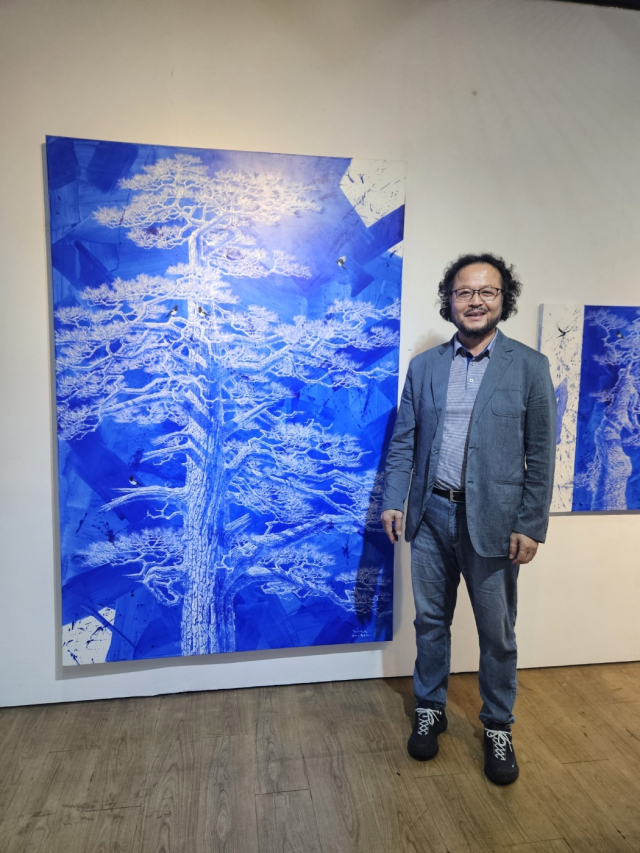 구명본 작가가 새로운 방식으로 작업한 신작 소나무 그림을 설명하고 있다.