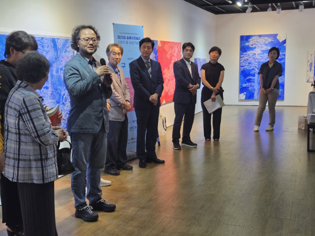 구명본 작가가 새로운 방식으로 작업한 신작 소나무 그림을 설명하고 있다.