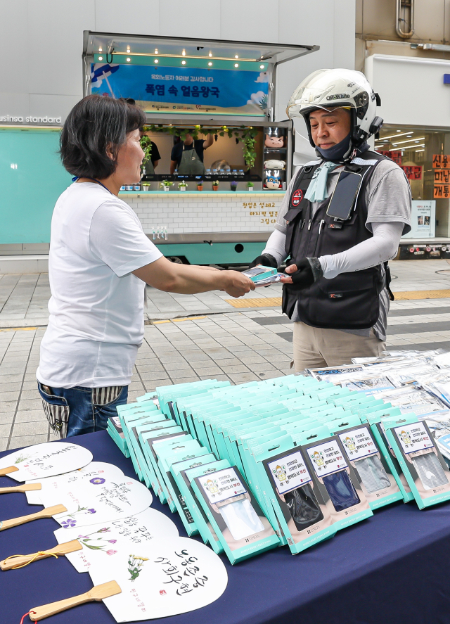 22일 오후 부산진구 서면 ABC 마트 앞 하트 조형물 인근에서 부산노동권익센터가 부산근로자건강센터, 부산진구자원봉사센터와 함께 여름철 더위와 싸우는 옥외노동자를 응원하는 캠페인 ‘폭염 속 얼음왕국’을 진행해 옥외노동자들에게 쿨 3종세트(쿨토시, 쿨스카프, 쿨타월)을 나눠주고 있다. 김종진 기자 kjj1761@