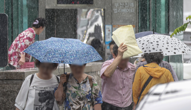 국지성 집중호우가 내린 지난해 7월 24일 오후 부산 동구의 한 거리에서 시민들이 갑작스럽게 내린 많은 비에 힘겹게 걸어가고 있다. 부산은 이날 새벽 일부 지역에 시간당 80mm 이상의 극한 호우가 내렸다. 김종진 기자 kjj1761@