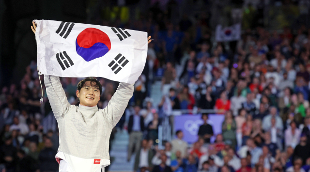 27일(현지시간) 프랑스 파리 그랑 팔레에서 열린 2024 파리 올림픽 펜싱 남자 사브르 경기에서 금메달을 따낸 오상욱이 태극기를 들고 세리머니를 하고 있다. 연합뉴스