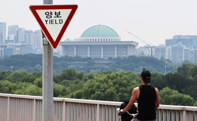 여야가 방송 4법과 전 국민 25만 원 지원법 등을 놓고 도돌이표 정국을 이어가는 가운데 4일 서울 마포구 서강대교에 설치된 교통표지판 너머로 국회의사당이 보인다. 연합뉴스