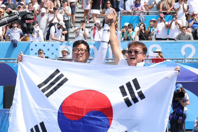 우리 선수단은 4일 경기가 모두 끝난 양궁 종목에서 총 5개의 금메달을 역대 최초로 석권하는 대위업을 이뤘다. 2024 파리 올림픽 양궁 남자 개인전 미국의 브레이디 엘리슨과의 결승에서 승리한 한국 김우진이 박성수 감독과 태극기를 들고 관중에게 인사하고 있다. 연합뉴스