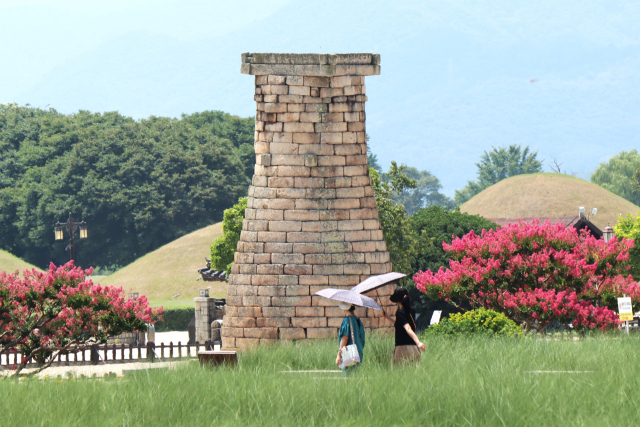 양산을 펼친 두 여성이 배롱나무꽃이 활짝 핀 첨성대 곁을 지나가고 있다. 남태우 기자