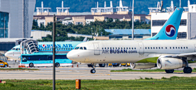 13일 김해국제공항 활주로에 에어부산 여객기가 대한항공 여객기 앞을 지나가고 있다. 김종진 기자 kjj1761@