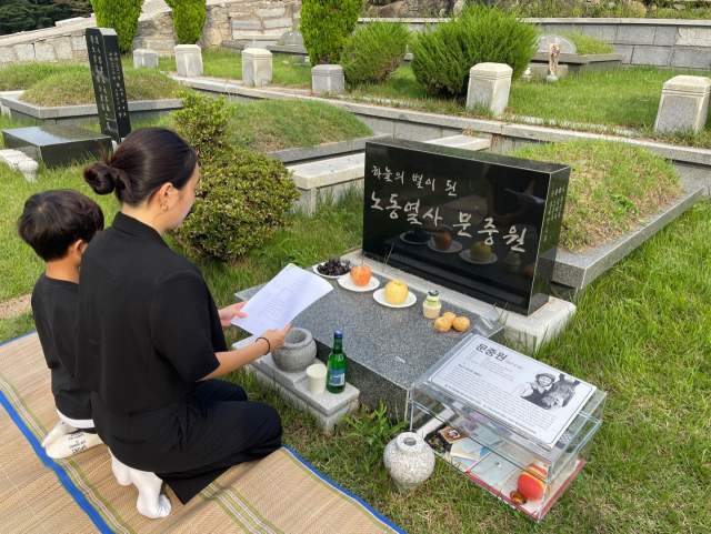 고 문중원 기수 유족들이 18일 양산 솥발산공원묘원 내 문 기수 묘소에 2심 판결문을 올리고 있다. 문 기수 부친 문군옥 씨 제공