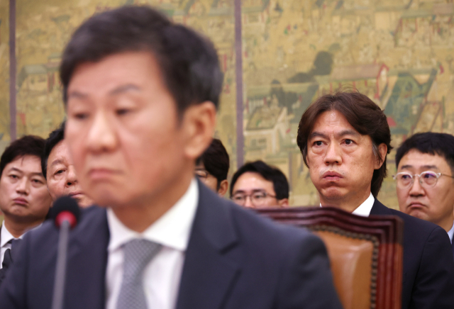 축구 국가대표팀 홍명보 감독이 2024년 9월 24일 국회에서 열린 문화체육관광위원회 전체회의에서 숨을 몰아쉬고 있다. 앞은 정몽규 대한축구협회장. 연합뉴스