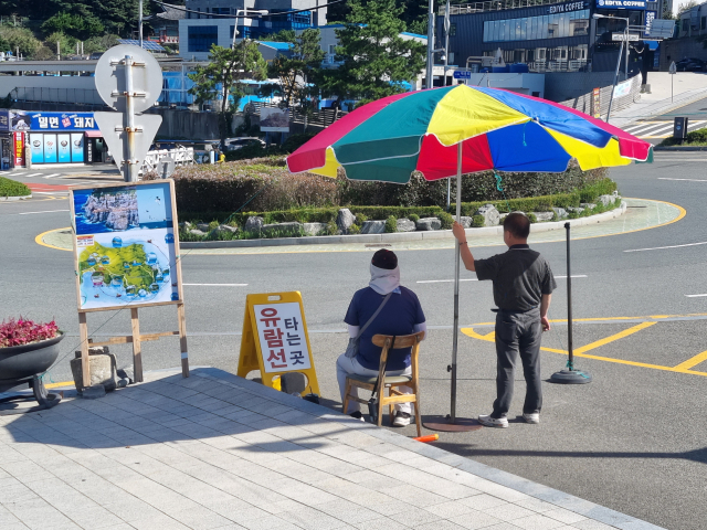 지난달 30일 부산 태종대 유원지 입구에 유람선 업체 측 관계자가 파라솔을 펴고 있다. 김준현 기자 joon@