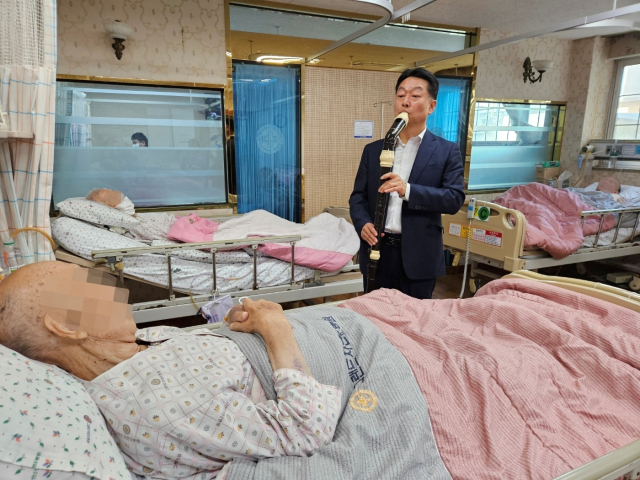 김정완 씨가 그랜드자연요양병원 병실을 찾아 리코더를 연주하고 있다.