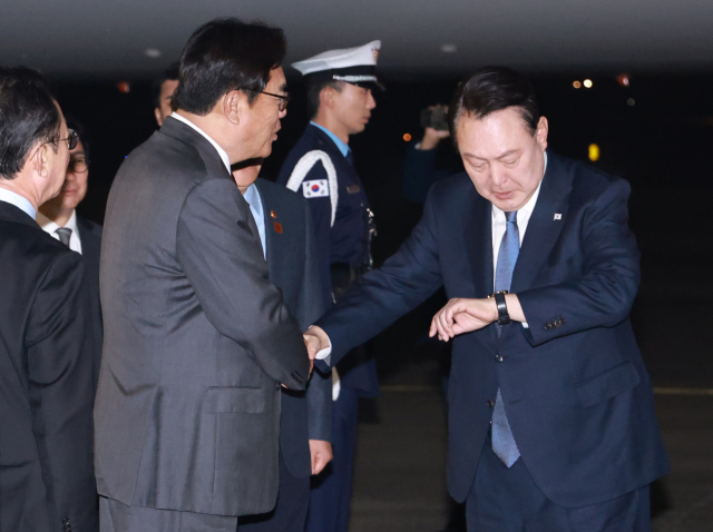 윤석열 대통령이 21일 31차 아시아태평양경제협력체(APEC) 및 19차 주요 20개국(G20) 정상회의 일정을 마치고 성남 서울공항에 도착한 뒤 마중 나온 정진석 비서실장과 인사를 나누며 시계를 보고 있다. 연합뉴스