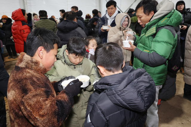 천성산 일출을 찾은 방문객이 1일 먹거리나눔 부스에서 떡국을 먹고 있다. 양산시 제공