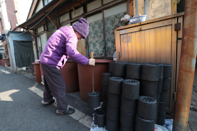 지난 14일 한 주민이 부산연탄은행이 배달한 연탄을 옮기고 있다. 정대현 기자 jhyun@