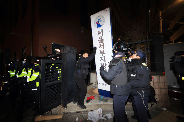 경찰 관계자들이 19일 서울 마포구 서울서부지방법원 후문에서 윤석열 대통령 구속에 반발한 시위대가 쓰러뜨린 현판을 세우고 있다. 연합뉴스