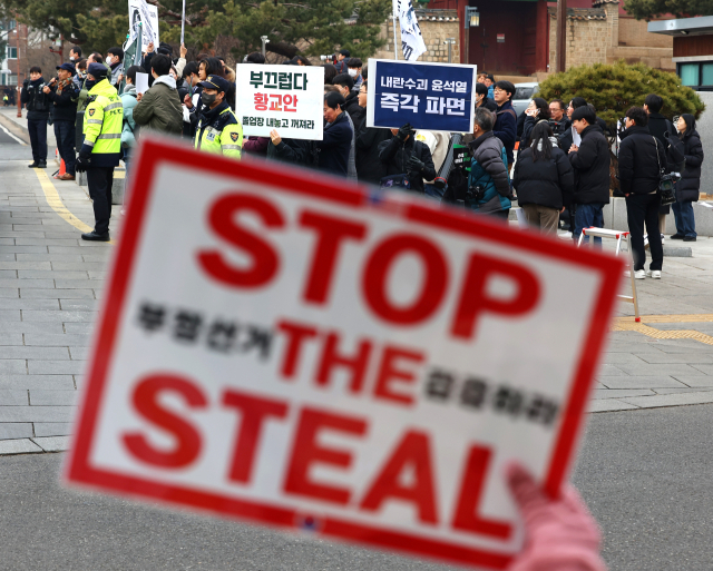 28일 서울 종로구 성균관대학교 앞에서 탄핵에 반대하는 윤석열 대통령의 지지자가 든 피켓 너머로 성균관대 긴급행동을 비롯한 윤석열 대통령 파면을 촉구하는 시민들이 '내란옹호세력 규탄 집회'를 하고 있다. 연합뉴스