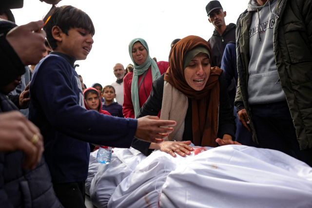 22일(현지 시간) 가자 지구 북쪽 베이트 라히아의 인도네시아 병원 앞마당에서 이스라엘의 공습으로 사망한 친척의 시신을 앞에 두고 팔레스타인 여성과 아이가 슬퍼하고 있다. AFP연합뉴스