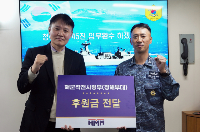 HMM 관계자가 지난 21일 청해부대 환송식에서 문무대왕함 임태웅 함장에게 후원금을 전달하고 화이팅을 외쳤다. HMM 제공