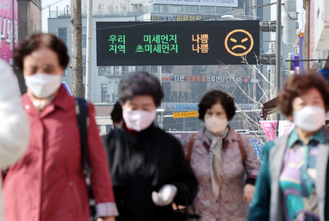 부산지역에 미세먼지와 초미세먼지 농도가 ‘나쁨’ 단계를 보인 25일 오전 부산 수영구 남천동의 미세먼지 상태 표시 안내 전광판 아래로 마스크를 착용한 시민들이 지나가고 있다. 정종회 기자 jjh@