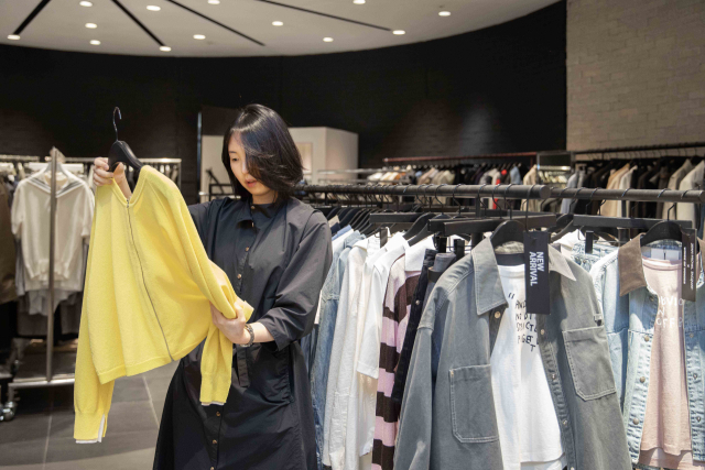 롯데백화점 관계자가 정기세일을 앞두고 러닝 상품 기획전(위)과 의류 특별전에 판매할 상품을 살펴보고 있다. 롯데백화점 제공