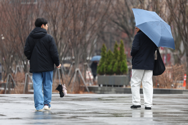 약한 비가 내리며 흐린 날씨를 보인 16일 서울 종로구 광화문 광장에서 우산을 쓴 시민과 우산을 접어 손에 든 시민이 서로를 바라보고 있다. 연합뉴스
