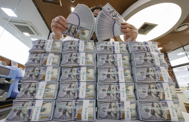 지난달 기업을 중심으로 국내 거주자 외화예금이 50억 달러 가까이 줄었다. 서울 중구 하나은행 외화 위·변조 대응센터 직원이 미국 달러를 정리하고 있다. 연합뉴스