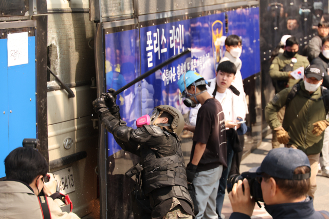 4일 서울 종로구 헌법재판소 인근에서 윤석열 대통령 지지 집회 참가자 중 한 명이 헌재의 윤 대통령 파면 결정에 경찰이 세운 가벽 사이로 보이는 차량을 부수고 있다. 연합뉴스