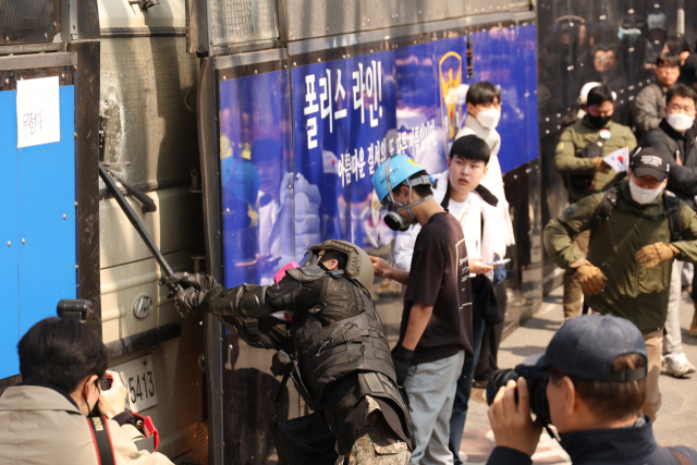 4일 서울 종로구 헌법재판소 인근에서 윤석열 대통령 지지 집회 참가자 중 한 명이 헌재의 윤 대통령 파면 결정에 경찰이 세운 가벽 사이로 보이는 차량을 부수고 있다. 연합뉴스