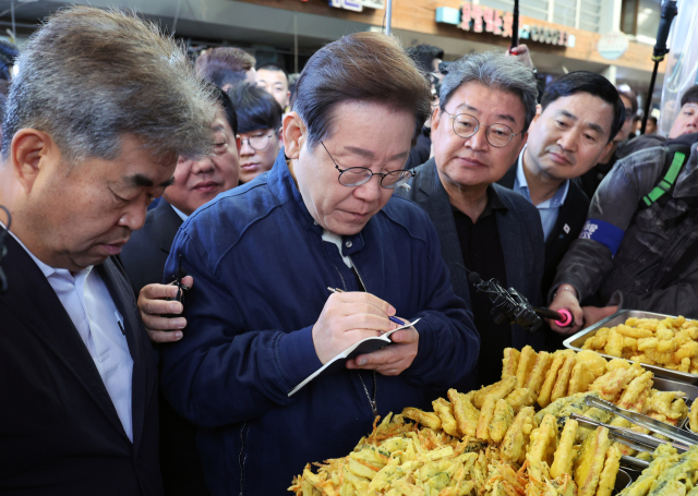 더불어민주당 이재명 대선 후보가 '골목골목 경청투어' 접경지역 방문 이틀째인 2일 강원도 철원군 동송전통시장에서 한 청년 상인과 대화하며 메모하고 있다. 연합뉴스