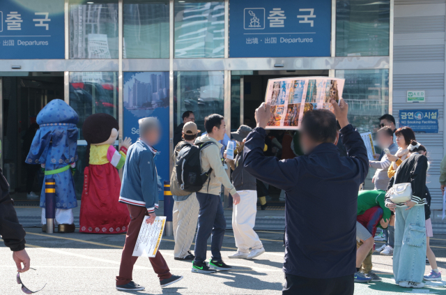 지난 2일 오전 부산항국제여객2터미널 출국장 입구에서 택시 기사들이 손에 팻말을 들고 크루즈 선박에서 하선하는 외국인 관광객을 상대로 호객 행위를 하고 있다. 정대현 기자 jhyun@