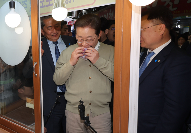 더불어민주당 이재명 대선 후보가 '골목골목 경청투어:국토종주편'에 나선 6일 충북 영동군 영동전통시장의 한 떡집에서 떡을 사먹고 있다. 연합뉴스