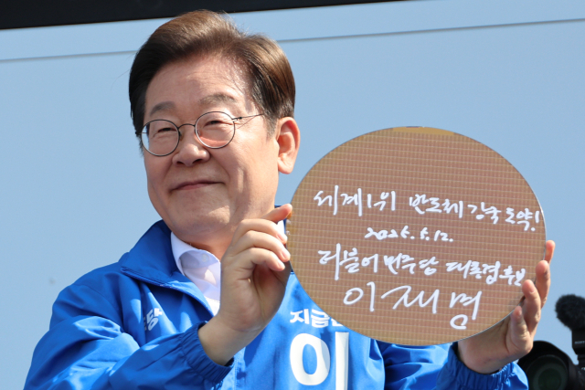 더불어민주당 이재명 대선 후보가 6·3 대통령선거 공식 선거운동 첫날인 12일 경기 화성시 동탄 센트럴파크 음악분수중앙광장 유세장에서 '세계1위 반도체 강국 도약!'이라고 쓰고 서명한 반도체 웨이퍼를 들어보이고 있다. 연합뉴스
