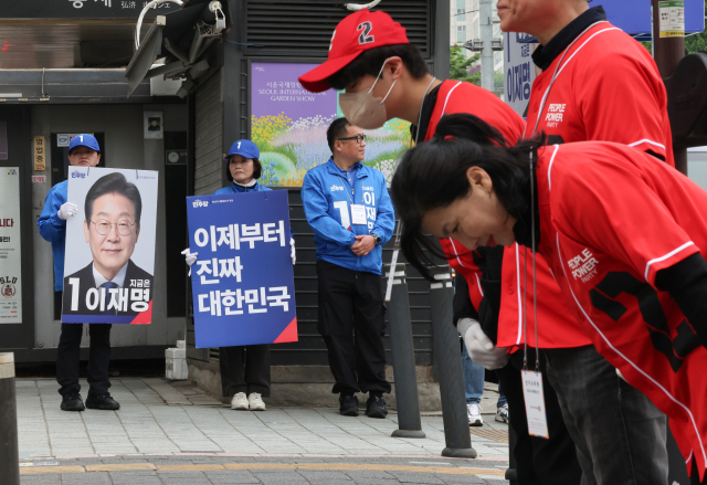 제21대 대통령 공식 선거운동 둘째 날인 13일 서울 서대문구 한 거리에서 기호 1번 더불어민주당 이재명, 2번 국민의힘 김문수 후보 선거운동원들이 시민들에게 인사하고 있다. 연합뉴스