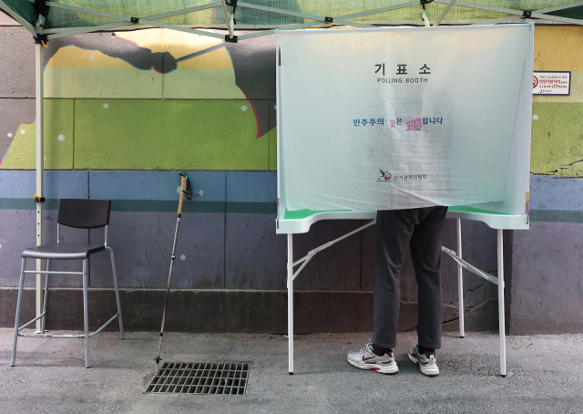 제21대 대통령 선거 사전투표 첫날인 29일 서울 중구 소공동주민센터에 설치된 사전투표소에서 거동이 불편한 유권자가 기표소에서 투표를 하고 있다. 연합뉴스