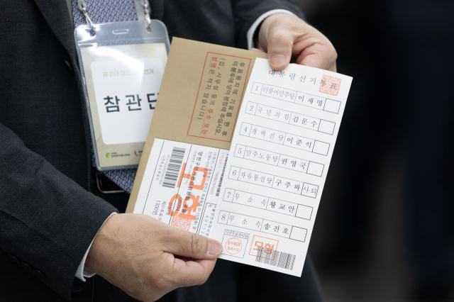 21대 대통령 선거 사전투표를 하루 앞둔 5월 28일 서울 광진구 중곡3동 주민센터에 마련된 사전투표소에서 투표 참관단이 인쇄된 투표용지를 들어보이고 있다. 연합뉴스