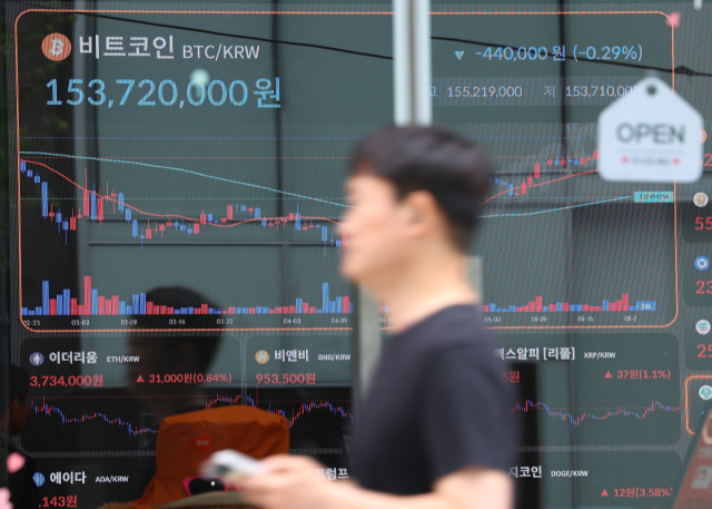 가상자산 비트코인이 역대 최고가인 11만 달러를 돌파한 다음 날인 지난달 23일 서울 서초구 빗썸라운지 강남본점 앞으로 시민이 지나고 있다. 연합뉴스