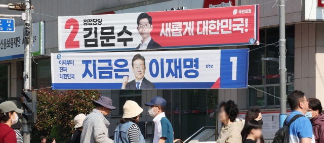제21대 대통령선거를 하루 앞둔 2일 부산 남구 대연교차로에 내걸린 더불어민주당 이재명 후보와 국민의힘 김문수 후보의 현수막 아래로 시민들이 지나가고 있다. 정종회 기자 jjh@