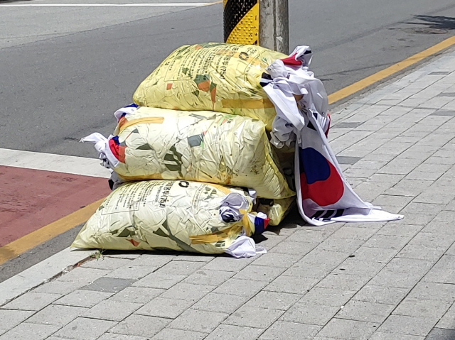 쓰레기봉투에 담겨 버려진 태극기. 연합뉴스