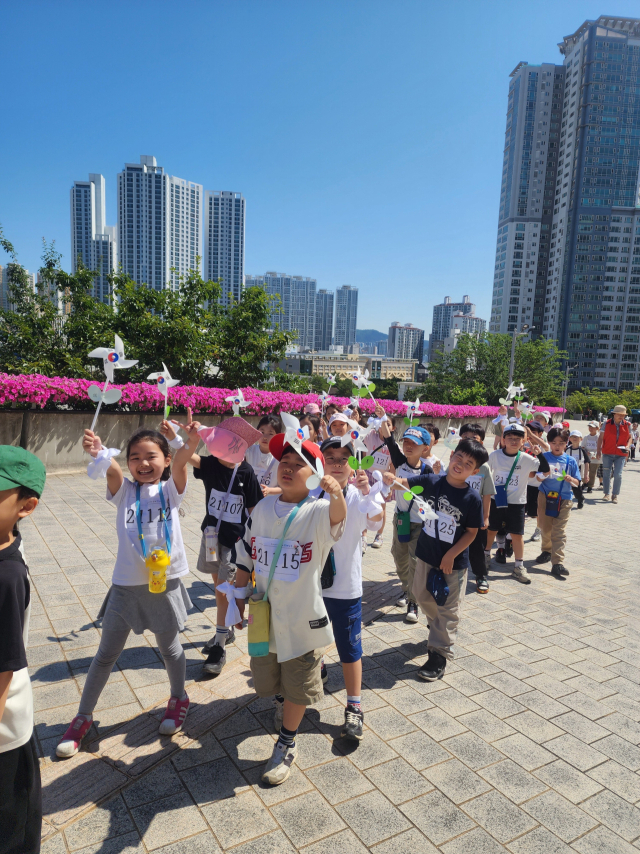 이달 초 ‘평화마라톤’에 참여한 부산 연제구 창신초등학교 학생들이 손에 바람개비를 쥔 채 마라톤 경로를 따라 걷고 있다. 창신초 제공