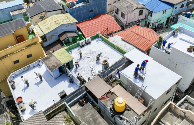 17일 부산 남구 전포대로 일원에서 쿨루프(Cool Roof) 봉사에 나선 자원봉사자들이 폭염 취약가구 20여 곳의 옥상에 친환경 열차단 페인트를 칠하고 있다. 부산시자원봉사센터가 주관한 이번 행사에는 좋은데이나눔재단, 신용보증재단, 해암문화재단, 국민연금공단 부산지역본부, 한국주택금융공사, BEXCO, 부산경제진흥원 등 7개 기업과 기관 임직원 및 대학생 봉사단 등 130여 명이 참여했다.