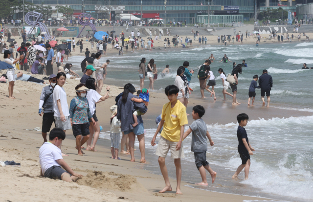 부산 해운대수욕장 개장 후 첫 휴일을 맞은 지난 22일 오후 해운대해수욕장을 찾은 관광객과 시민들이 백사장에서 물놀이를 즐기고 있다. 정종회 기자 jjh@