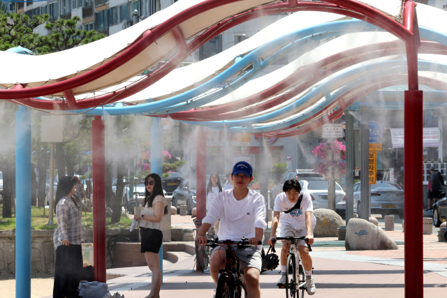 부산 지역에 폭염특보가 이어진 지난 7월 2일 수영구 광안리해수욕장을 찾은 시민과 관광객들이 쿨링포그 아래를 지나며 더위를 식히고 있다. 정종회 기자 jjh@