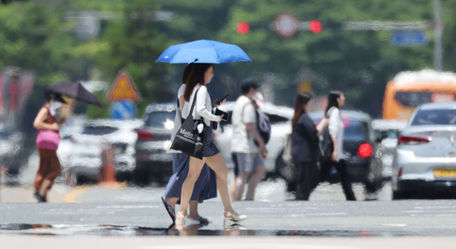 7일 부산 해운대구 벡스코 인근 도로에서 시민들이 지열로 아지랑이가 피어오르는 횡단보도를 건너고 있다. 정종회 기자 jjh@