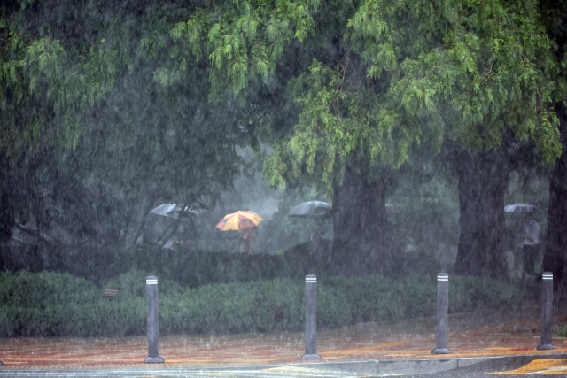 서울 서남권에 호우주의보가 발효된 8일 서울 영등포구 여의도 국회에서 시민들이 우산을 쓰고 있다. 연합뉴스