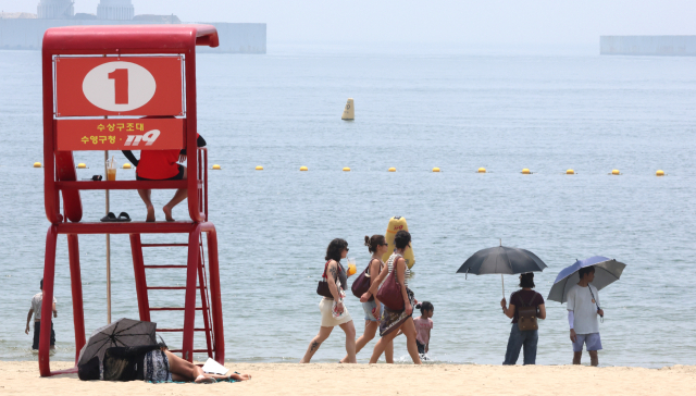 여름 더위가 본격적으로 시작된다는 절기 ‘소서(小暑)’인 7일 부산 수영구 광안리해수욕장을 찾은 관광객들이 백사장을 걷고 있다. 연합뉴스