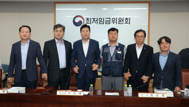 이인재 최저임금위원장(왼쪽 두 번째)이 10일 정부세종청사에서 열린 제12차 전원회의에서 내년 최저임금을 시간당 1만320원으로 17년만에 합의로 결정한 뒤 공익위원-사용자위원-근로자위원과 손을 잡고 있다. 연합뉴스