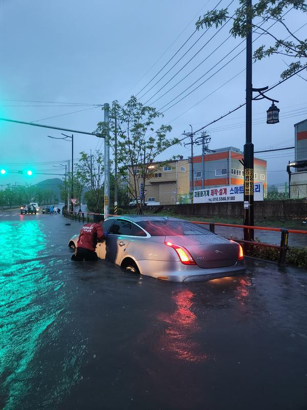 지난 13일 경남 김해시 주촌면 골든루트로 사거리에서 폭우로 침수된 차량을 119구조대가 안전지대로 밀어내고 있다. 경남소방본부제공