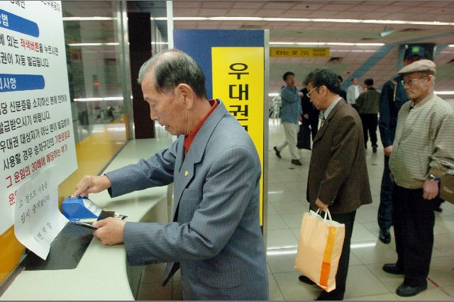 2004년 11월 부산지하철 1호선 서면역 무임우대권 발급기 앞에서 한 승객이 노인 신분증을 제시하고 무임권 발급버튼을 누르고 있다. 부산일보DB